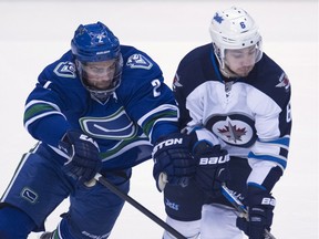 Dan Hamhuis (left) battles Alexander Burmistrov for the puck when the Canucks met the Jets March 14 at Rogers Arena.