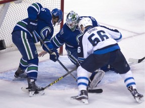 Vancouver Canucks defenceman Luca Sbisa (5) tries to stop Winnipeg Jets Marko Dano from getting a shot past Vancouver Canucks goalie Jacob Markstrom (25) during second period NHL action in Vancouver on Monday, March 14, 2016.