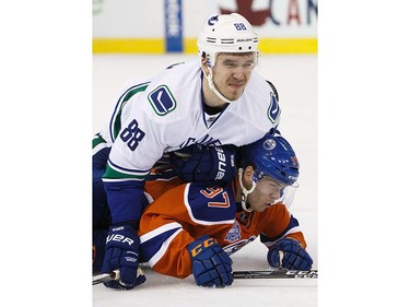 Connor McDavid #97 of the Edmonton Oilers is flattened by Nikita Tryamkin #88 of the Vancouver Canucks on April 6, 2016 at Rexall Place in Edmonton, Alberta, Canada. The game is the final game the Oilers will play at Rexall Place before moving to Rogers Place next season. (Photo by Codie McLachlan/Getty Images)