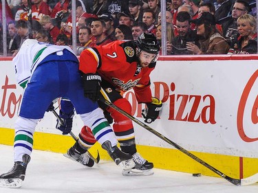 T.J. Brodie #7 of the Calgary Flames fights for the puck against Jannik Hansen #36 of the Vancouver Canucks during an NHL game at Scotiabank Saddledome on April 7, 2016 in Calgary, Alberta, Canada. (Photo by Derek Leung/Getty Images)