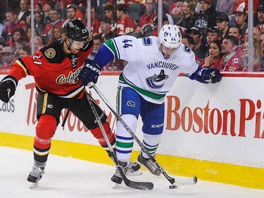Dougie Hamilton #27 of the Calgary Flames battles Matt Bartkowski #44 of the Vancouver Canucks for the puck during an NHL game at Scotiabank Saddledome on April 7, 2016 in Calgary, Alberta, Canada. (Photo by Derek Leung/Getty Images)