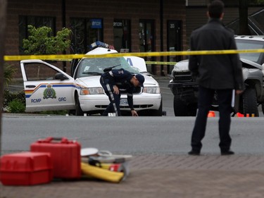 A Saanich police officer examines the scene of the crash involving a police car and a pickup truck in Langford, B.C., Tuesday, April 5, 2016. RCMP Const. Sarah Beckett was killed in the crash.