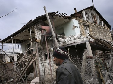 An ethnic Armenian man walks past a destroyed house during the fighting in Martakert province in the separatist region of Nagorno-Karabakh, Azerbaijan, Monday, April 4, 2016. Fighting raged Monday around Nagorno-Karabakh, with Azerbaijan saying it lost three of its troops in the separatist region while inflicting heavy casualties on Armenian forces and the Armenian president warning that the hostilities could slide into a full-scale war.