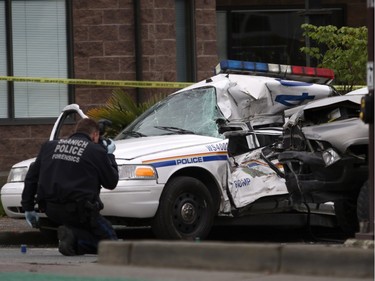 An Investigator examines the scene of the crash involving a police car and a pickup truck in Langford, B.C., Tuesday, April 5, 2016. RCMP Const. Sarah Beckett was killed in the crash.
