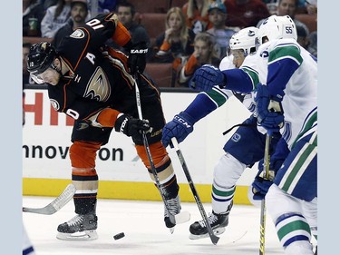 Anaheim Ducks right wing Corey Perry (10) takes a shot under pressure from Vancouver Canucks right wing Emerson Etem, center, and defenseman Alex Biega (55) during the second period of an NHL hockey game in Anaheim, Calif., Friday, April 1, 2016. (AP Photo/Alex Gallardo)