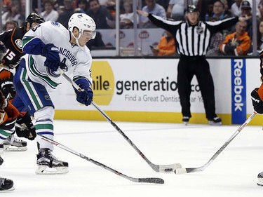 Vancouver Canucks center Bo Horvat, center left, takes a shot against Anaheim Ducks defensemen Clayton Stoner, left, and Sami Vatanen, right, of Finland, during the third period of an NHL hockey game in Anaheim, Calif., Friday, April 1, 2016. The Canucks won 3-2. (AP Photo/Alex Gallardo)