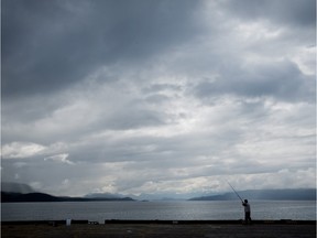 Chang Shun Huang, of Burnaby, B.C., is silhouetted as he fishes on the end of a wharf in Sandspit, B.C., on Moresby Island in Haida Gwaii on Friday August 16, 2013.
