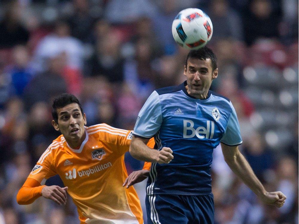 Vancouver Whitecaps' Andrew Jacobson, right, gets his head on the ball in front of Houston Dynamo's Cristian Maidana during the first half of an MLS soccer game in Vancouver, B.C., on Saturday March 26, 2016.