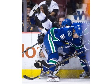Los Angeles Kings' Drew Doughty, left, is upended by Vancouver Canucks' Chris Tanev, back right, behind Markus Granland (60), of Finland, during the first period of an NHL hockey game in Vancouver, B.C., on Monday April 4, 2016.