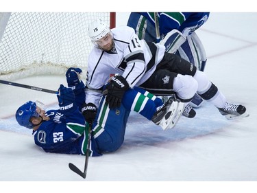 Los Angeles Kings' Andy Andreoff, top, falls on Vancouver Canucks' Henrik Sedin, of Sweden, during the second period of an NHL hockey game in Vancouver, B.C., on Monday April 4, 2016.