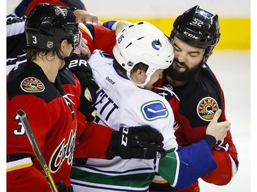 Vancouver Canucks' Derek Dorsett, centre, fights with Calgary Flames' Brandon Bollig (52) during first period NHL hockey action in Calgary, Thursday, April 7, 2016.THE CANADIAN PRESS/Jeff McIntosh