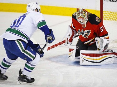 Vancouver Canucks' Brendan Gaunce, left, has his sht deflected by Calgary Flames goalie Joni Ortio, from Finland, during first period NHL hockey action in Calgary, Thursday, April 7, 2016.THE CANADIAN PRESS/Jeff McIntosh