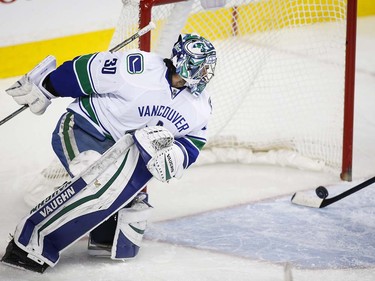 Vancouver Canucks goalie Ryan Miller, right, looks back as a teammate swats the puck away from the net during first period NHL hockey action against the Calgary Flames in Calgary, Thursday, April 7, 2016.THE CANADIAN PRESS/Jeff McIntosh