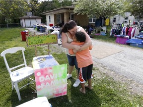 Donnie Davis gives Tristan Jacobson a kiss outside their home in Springfield, Mo. Tristan has been living with with Donnie and Jimmy Davis. He has set up a lemonade stand to raise money for his adoption.