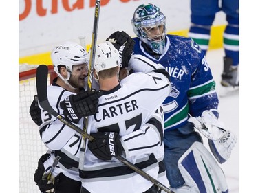 Los Angeles Kings' Kyle Clifford, left, Jeff Carter and Andy Andreoff celebrate Clifford's goal against Vancouver Canucks' goalie Ryan Miller, back right, during the second period of an NHL hockey game in Vancouver, B.C., on Monday April 4, 2016.