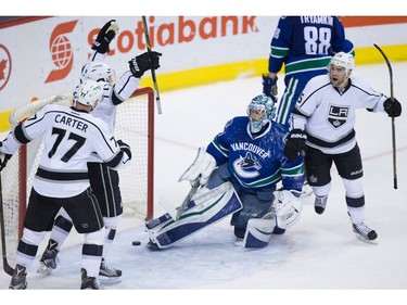 Los Angeles Kings' Jeff Carter, left, Kyle Clifford and Andy Andreoff, right, celebrate Clifford's goal against Vancouver Canucks' goalie Ryan Miller during the second period of an NHL hockey game in Vancouver, B.C., on Monday April 4, 2016.