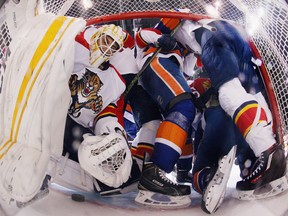 Roberto Luongo #1 of the Florida Panthers is pushed aside as players from the Panthers and the New York Islanders converge in the crease during the 2016 NHL Stanley Cup Playoffs.