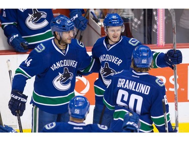 Vancouver Canucks' Matt Bartkowski, left, Jared McCann, top right, and Markus Granland, of Finland, celebrate McCann's goal against the Los Angeles Kings during the second period of an NHL hockey game in Vancouver, B.C., on Monday April 4, 2016.
