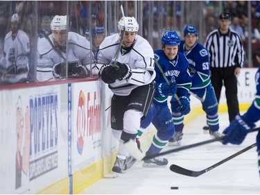 Los Angeles Kings' Milan Lucic, front left, passes the puck while being pressured by Vancouver Canucks' Derek Dorsett during the first period of an NHL hockey game in Vancouver, B.C., on Monday April 4, 2016.