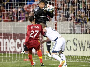 Real Salt Lake goalkeeper Nick Rimando (18) makes a save in front of midfielder John Stertzer (27) and Vancouver Whitecaps defender Jordan Harvey (2) during the first half at Rio Tinto Stadium.
