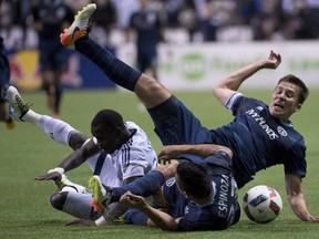 Sporting Kansas City defender Matt Besler (5) and midfielder Roger Espinoza (27) fight for control of the ball with Vancouver Whitecaps forward Kekuta Manneh (23) during the second half of MLS soccer action in Vancouver, B.C. Wednesday, April 27, 2015.