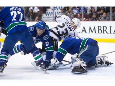 Vancouver Canucks' Nikita Tryamkin, left, of Russia, and Los Angeles Kings' Dustin Brown collide as Canucks' goalie Ryan Miller covers up the puck during the first period of an NHL hockey game in Vancouver, B.C., on Monday April 4, 2016.