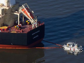 A spill response boat secures a boom around the bulk carrier cargo ship MV Marathassa after a bunker fuel spill on Burrard Inlet in Vancouver, B.C., on April 9, 2015.