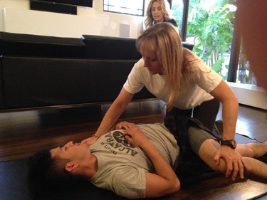 Jockey Mario Gutierrez works on stretching with fitness coach Sabrina Perruzi as his wife Rebecca looks on in their home. He’s now in the top 10 in U.S. jockey rankings.