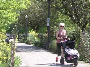 A woman pushes a stroller through Nelson Park in Vancouver's West End on Tuesday.