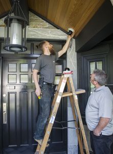 Stuart Armour (right), owner of Affordable Security Systems, and Victor Martinez (left), his head technician, instal a security camera at the front door of a New Westminster home.
