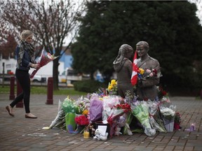 A woman brings flowers to a bronze statue created by artist Derek Rowe, titled RCMP and Child, in front of the West Shore RCMP detachment in Langford, B.C., Wednesday, April 6, 2016. RCMP Const. Sarah Beckett died early Tuesday after an early morning collision with a pickup truck.