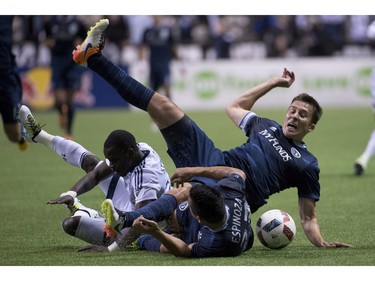 Sporting Kansas City defender Matt Besler (5) and midfielder Roger Espinoza (27) fight for control of the ball with Vancouver Whitecaps forward Kekuta Manneh (23) during the second half of MLS soccer action in Vancouver, B.C. Wednesday, April 27, 2015.