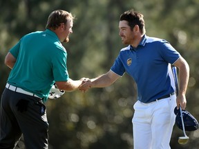 J.B. Holmes of the United States and Louis Oosthuizen of South Africa shake hands after finishing on the 18th green during the final round of the 2016 Masters Tournament at Augusta National Golf Club on April 10, 2016 in Augusta, Georgia.