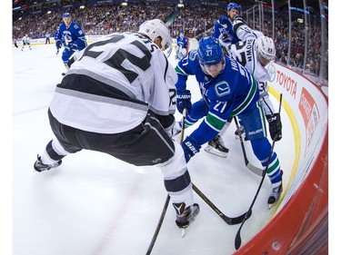Vancouver Canucks' Ben Hutton, centre, battles for the puck against Los Angeles Kings' Trevor Lewis, left, and Dustin Brown, right, during the first period of an NHL hockey game in Vancouver, B.C., on Monday April 4, 2016.