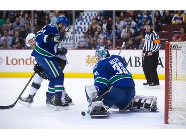 Vancouver Canucks' goalie Ryan Miller, right, stops Los Angeles Kings' Trevor Lewis, back left, as Canucks' Matt Bartkowski defends during the first period of an NHL hockey game in Vancouver, B.C., on Monday April 4, 2016.