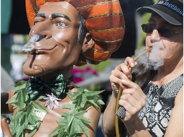 A joint is smoked at a vendor's display at the annual 4:20 marijuana event at it's new location, Sunset Beach, Vancouver April 20 2016.