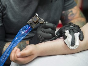 Bill Gaspari, one of Adrenaline Vancity's senior tattoo artists, inks a tattoo on client's arm Thursday.