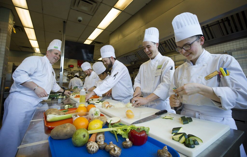 VCC Instructor John Lewis (left) speaks with culinary students, as they prepare their dishes during class at the downtown campus in Vancouver.