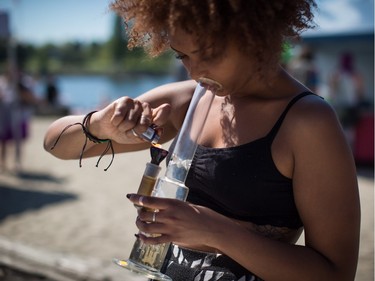 A woman takes a hit from a bong during the annual 4/20 cannabis culture celebration at Sunset Beach in Vancouver, B.C., on Wednesday April 20, 2016.