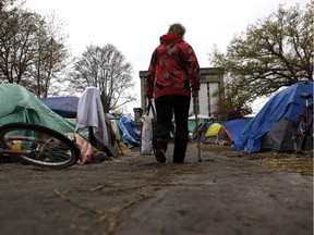 A resident walks down a path at the tent city on Victoria's courthouse lawn in April. The government has filed another injunction to have the site closed down.