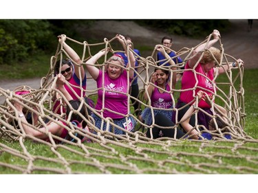 A group of participants work together while trying to crawl through a giant net while taking part in the Woman2Warrior event at Swangard Stadium and Central Park in Burnaby, BC, May, 15, 2016. Funds raised through this all-women charity obstacle adventure race will benefit the BC Lions Society and Easter Seals camps for children with disabilities.