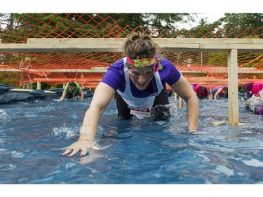 A woman crawls through a water obstacle while taking part in the Woman2Warrior event at Swangard Stadium and Central Park in Burnaby, BC, May, 15, 2016. Funds raised through this all-women charity obstacle adventure race will benefit the BC Lions Society and Easter Seals camps for children with disabilities.