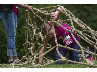 A woman crawls under a giant net while taking part in the Woman2Warrior event at Swangard Stadium and Central Park in Burnaby, BC, May, 15, 2016. Funds raised through this all-women charity obstacle adventure race will benefit the BC Lions Society and Easter Seals camps for children with disabilities.