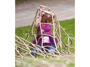 A woman gets tangled up in a giant net while trying to crawl through while taking part in the Woman2Warrior event at Swangard Stadium and Central Park in Burnaby, BC, May, 15, 2016. Funds raised through this all-women charity obstacle adventure race will benefit the BC Lions Society and Easter Seals camps for children with disabilities.