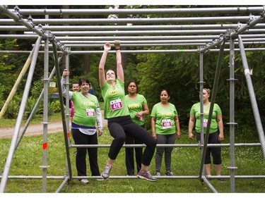 A woman is cheered on by her teammates while make her way through the monkey bars obstacle while taking part in the Woman2Warrior event at Swangard Stadium and Central Park in Burnaby, BC, May, 15, 2016. Funds raised through this all-women charity obstacle adventure race will benefit the BC Lions Society and Easter Seals camps for children with disabilities.