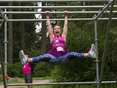 A woman poses for a photo while making her way through the monkey bars obstacle while taking part in the Woman2Warrior event at Swangard Stadium and Central Park in Burnaby, BC, May, 15, 2016. Funds raised through this all-women charity obstacle adventure race will benefit the BC Lions Society and Easter Seals camps for children with disabilities.