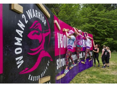 Women make their way along a wall while taking part in the Woman2Warrior event at Swangard Stadium and Central Park in Burnaby, BC, May, 15, 2016. Funds raised through this all-women charity obstacle adventure race will benefit the BC Lions Society and Easter Seals camps for children with disabilities.