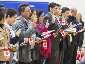Immigrants take the oath of citizenship. Studies suggests immigrants in recent decades have become more of a financial burden on Canada's welfare, health and education systems.