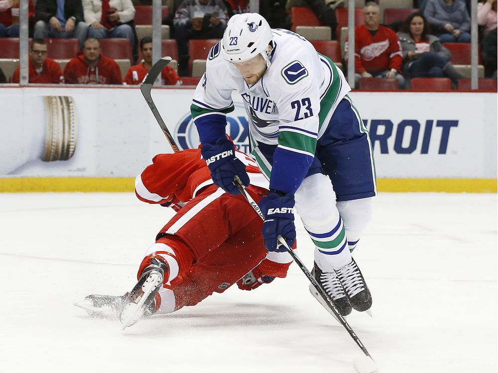 Detroit Red Wings left wing Justin Abdelkader (8) and Vancouver Canucks defenseman Alexander Edler (23) collide going for the puck in the first period of an NHL hockey game Friday, Dec. 18, 2015 in Detroit.