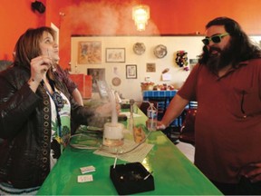 The Green Ceiling owner Ashley Abraham, left, samples smoke from a bong with a customer at her new lounge in Victoria.